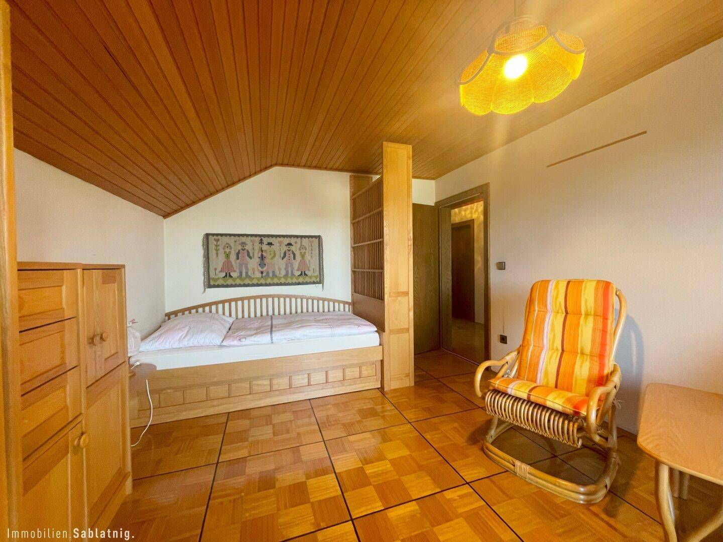 Gemütliches Schlafzimmer mit Holzbett, Holzdecke und traditioneller Dekoration.