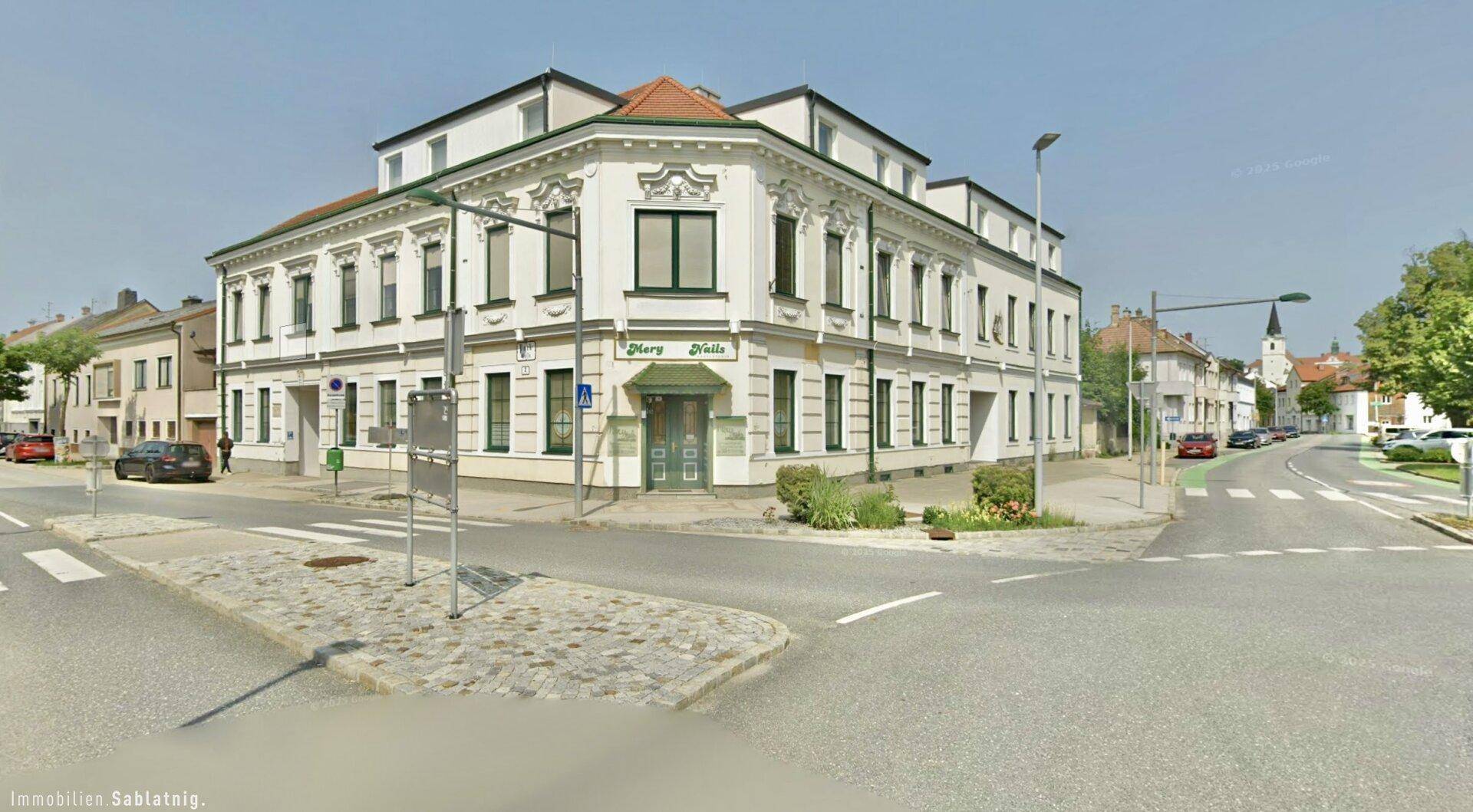 Historisches Eckgebäude an einer belebten Straße mit Geschäften im Erdgeschoss.