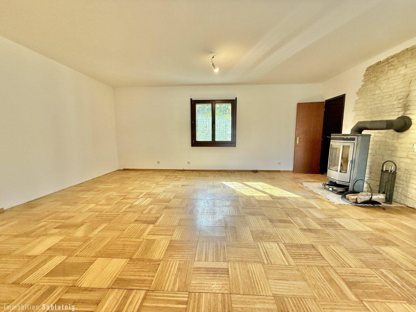 Heller Wohnbereich mit Parkettboden und Kaminofen, ideal für entspannte Stunden.