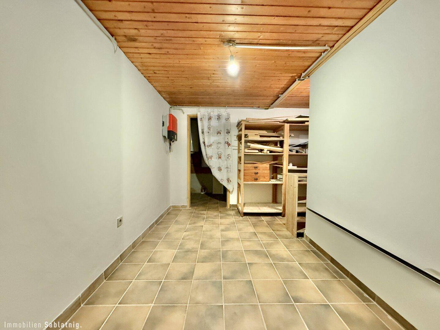 Praktischer Kellerraum mit Fliesenboden und Holzdecke, ideal als Abstellfläche.