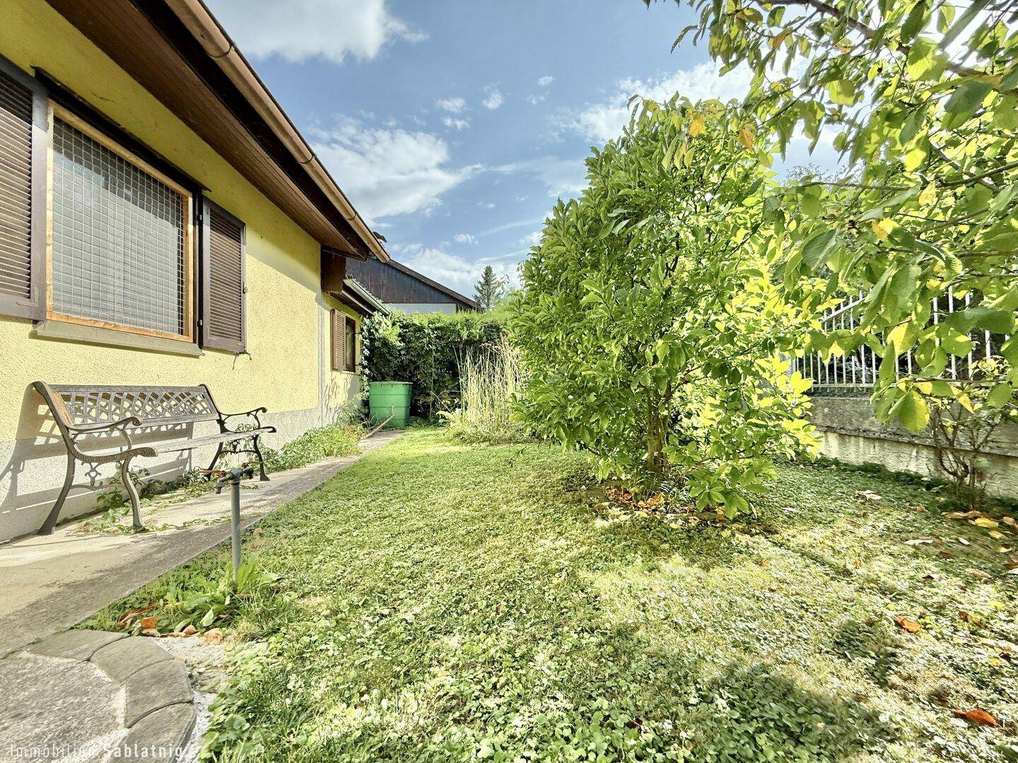 Kleiner Gartenbereich mit Sitzbank und Obstbaum, ideal zum Entspannen.