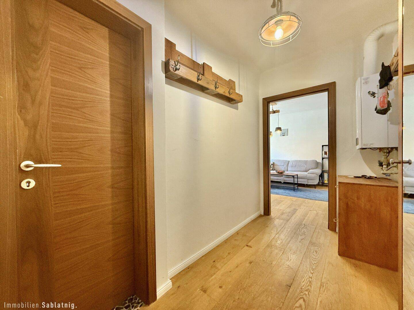 Heller Flur mit Holzboden, Garderobe und Zugang zu den Wohnräumen.