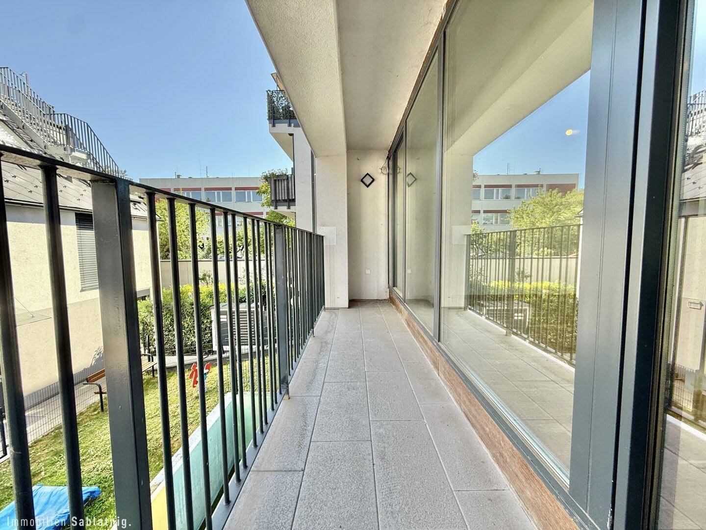 Langer, leerer Balkon mit Fliesenboden und Metallgeländer, ideal für Entspannung im Freien.