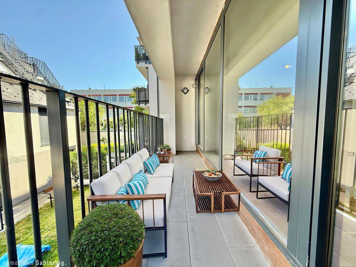 Möblierter Balkon mit Sitzgelegenheiten und Blick auf die umliegenden Gebäude, ideal zum Entspannen.