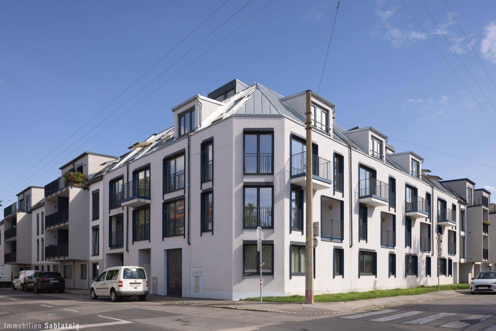 Eckansicht eines modernen Wohngebäudes mit weißer Fassade und dunklen Fensterrahmen, stilvolle Architektur.