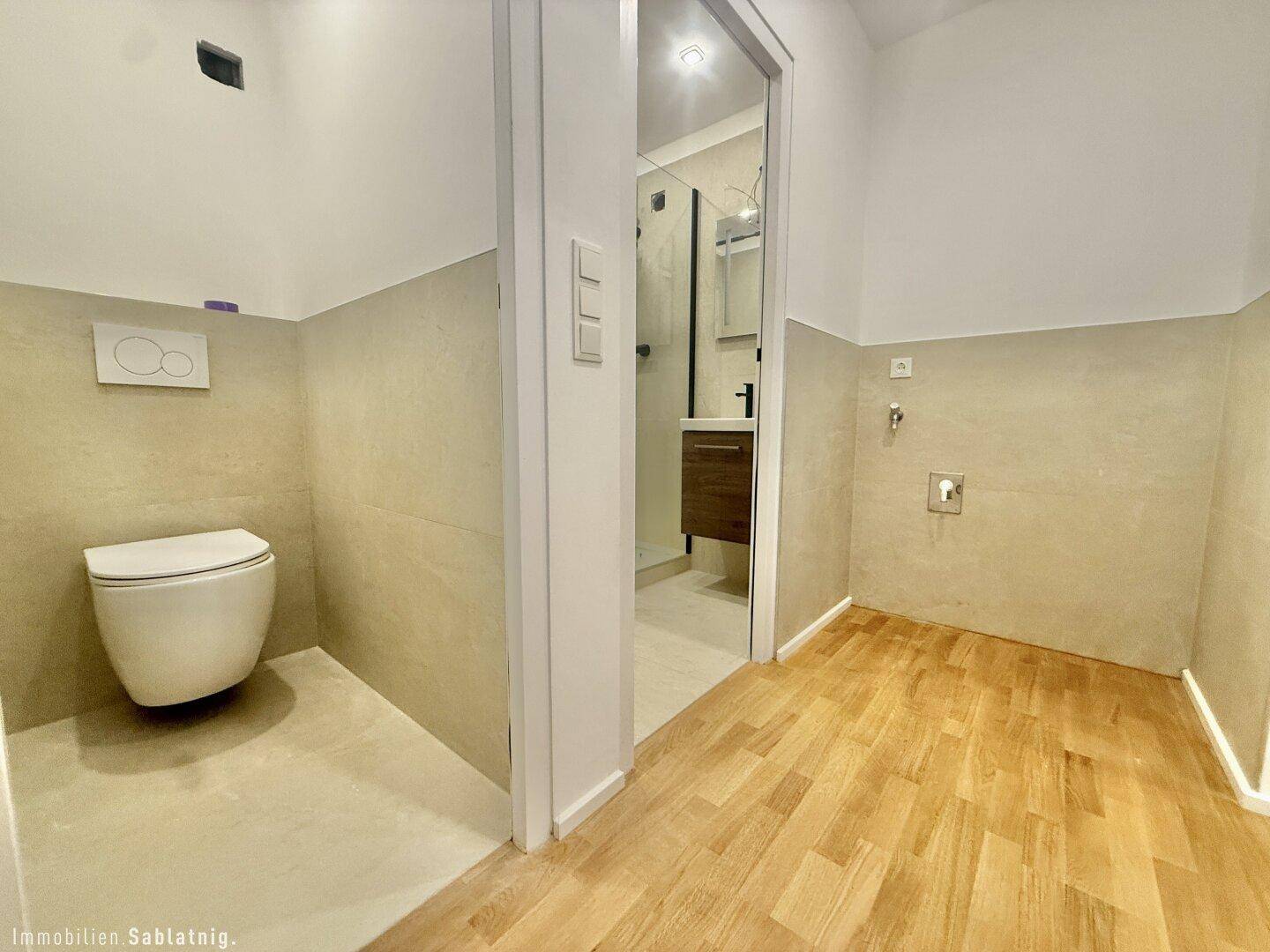Modernes Badezimmer mit wandhängendem WC, beigefarbenen Fliesen und begehbarer Dusche.