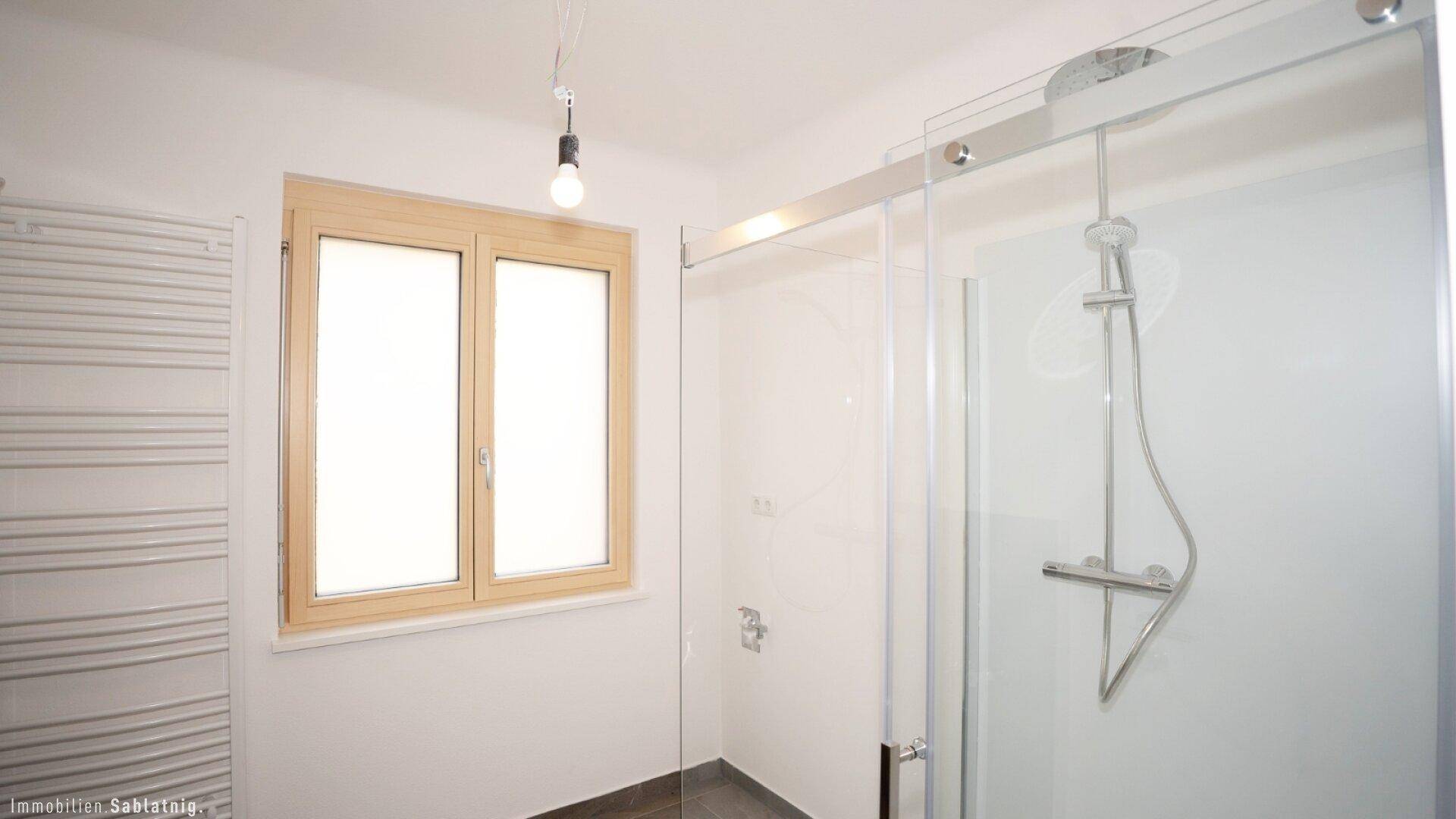 Modernes Badezimmer mit Duschkabine, Fenster und beheiztem Handtuchhalter.