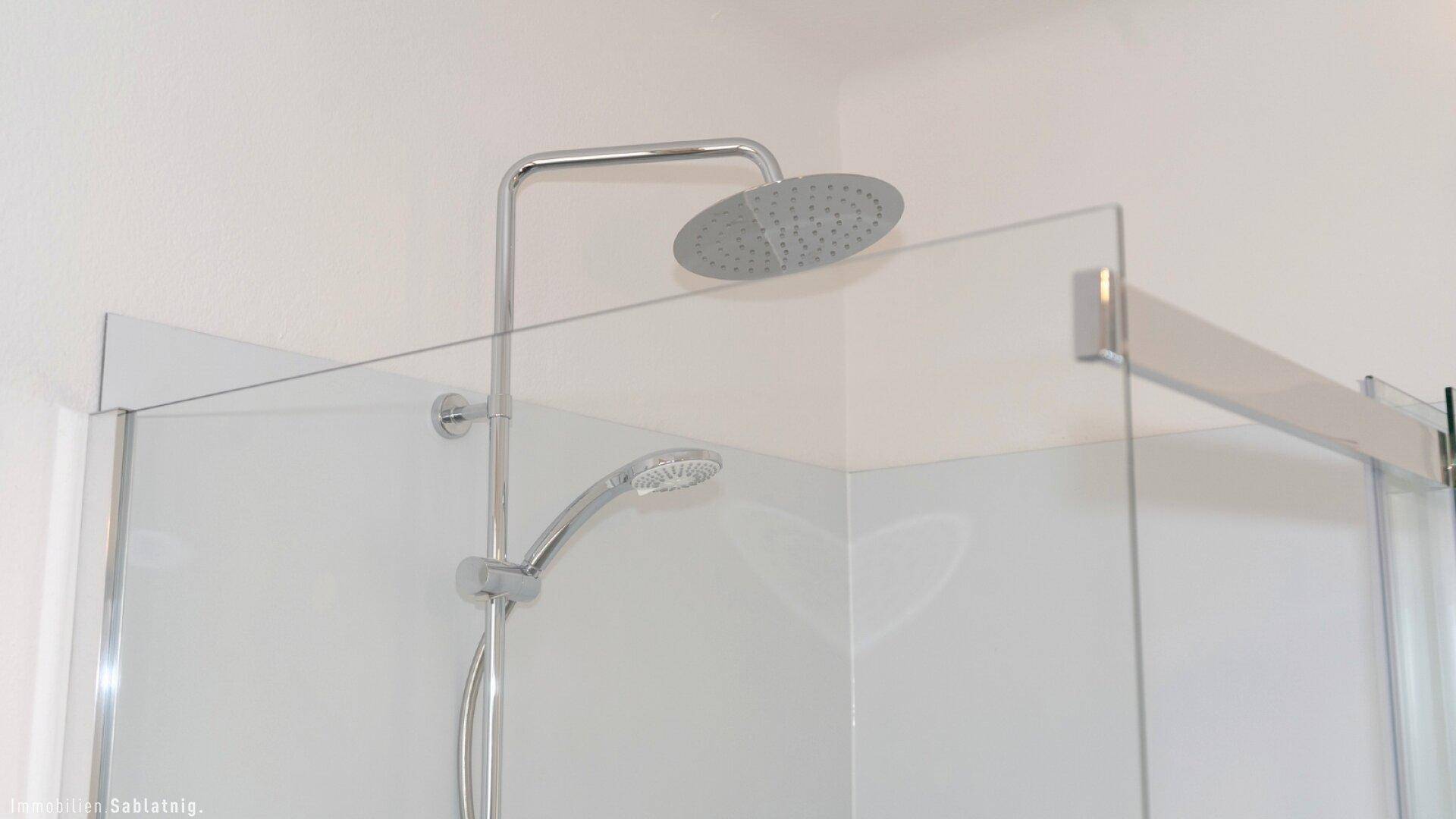 Detailansicht einer modernen Duschkabine mit Regenduschkopf und Glasabtrennung.