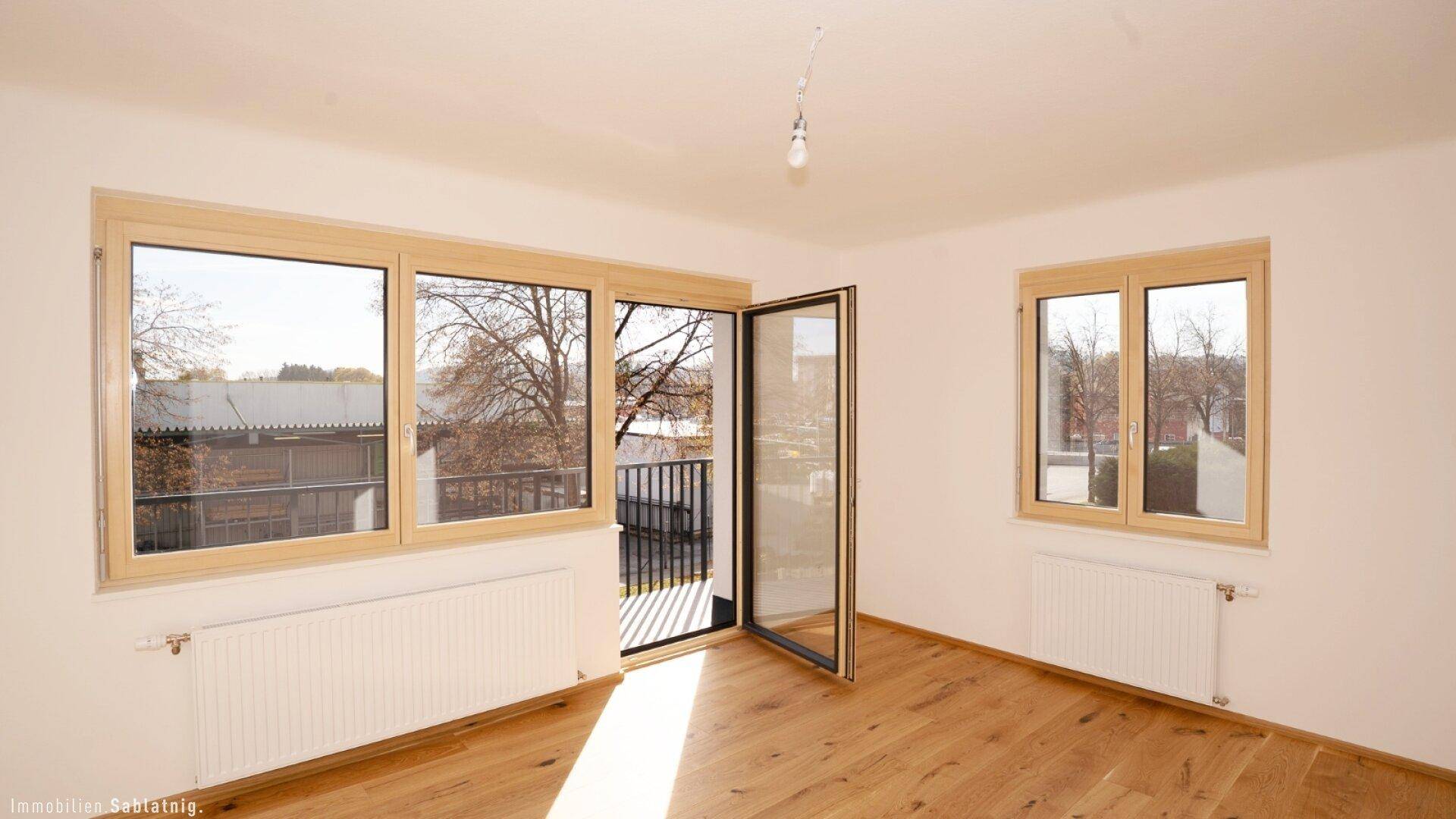 Heller Raum mit Eichenparkett und Zugang zu einem Balkon, ideal für Wohn- oder Schlafbereich.