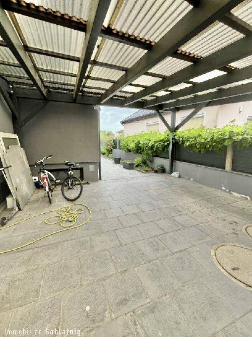 Geräumiger überdachter Bereich, ideal als Carport oder Abstellfläche, mit Zugang zum Garten.