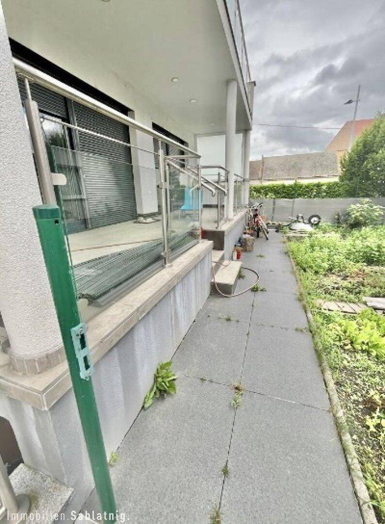 Seitlicher Zugang zum Gartenbereich mit gepflastertem Weg und üppiger Vegetation.