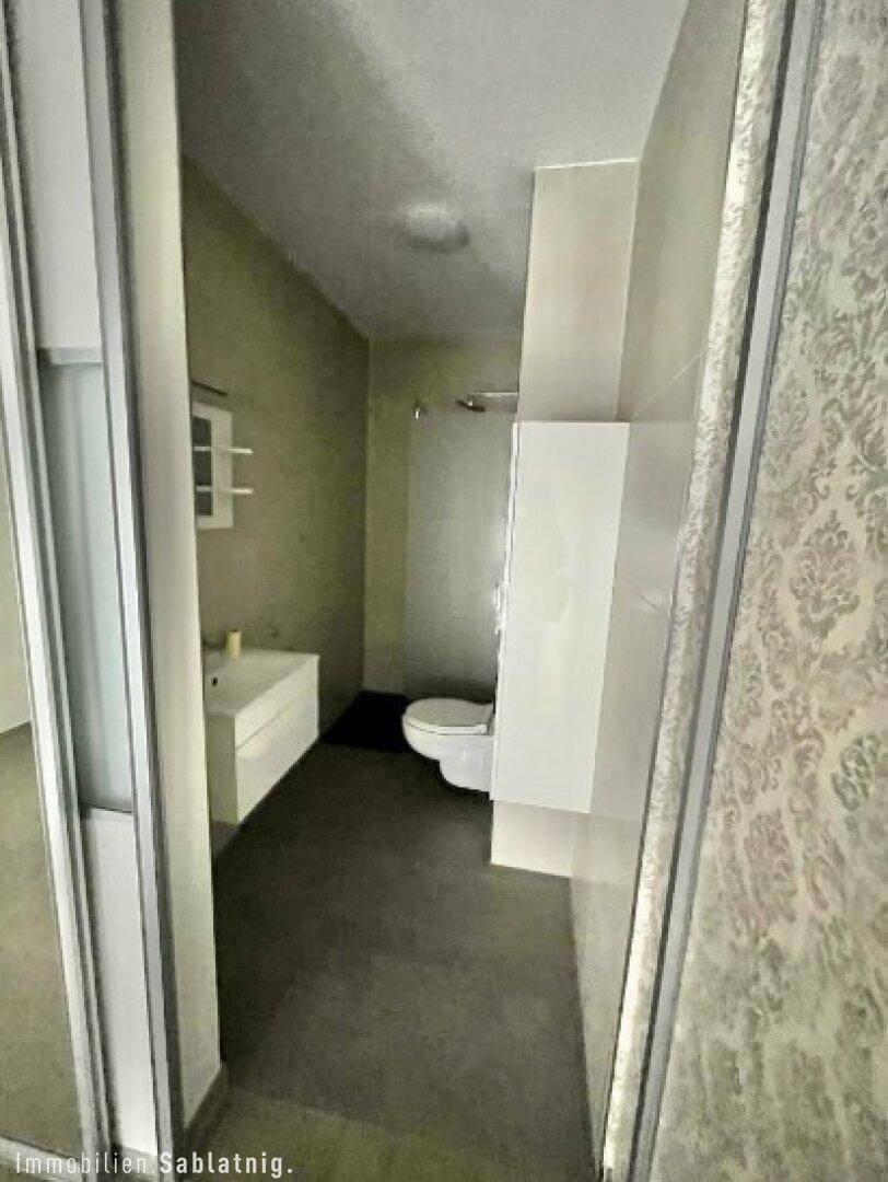 Modernes Badezimmer mit Duschbereich, Wand-WC und minimalistischem Design.