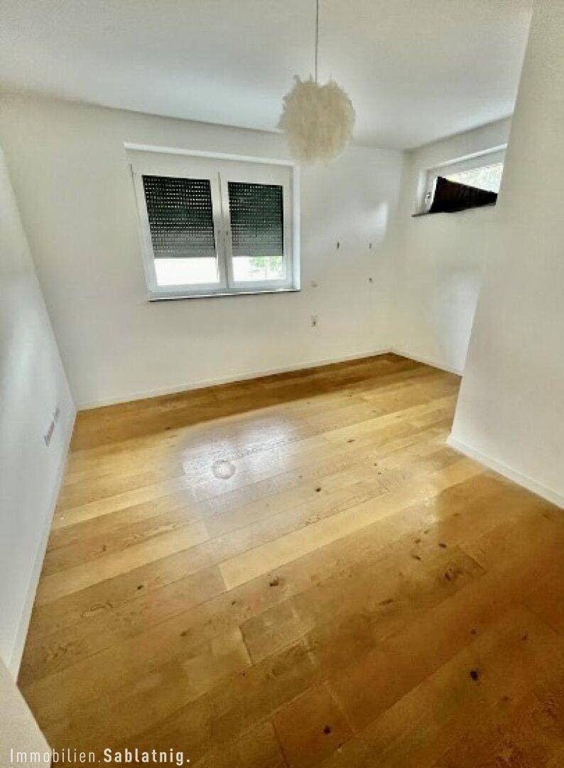 Helles Schlafzimmer mit Holzboden und Fenster, bereit zur Einrichtung.