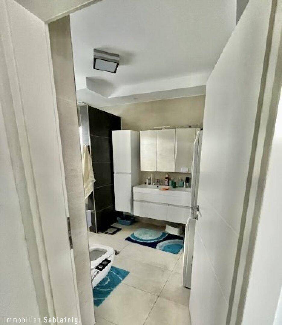 Modernes Badezimmer mit Doppelwaschbecken, Spiegelschrank und hellen Fliesen.