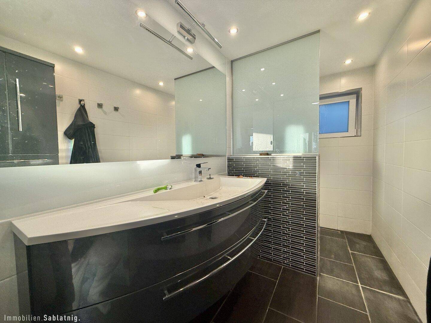 Modernes Badezimmer mit stilvollem Waschtisch, großem Spiegel und Fliesenboden.