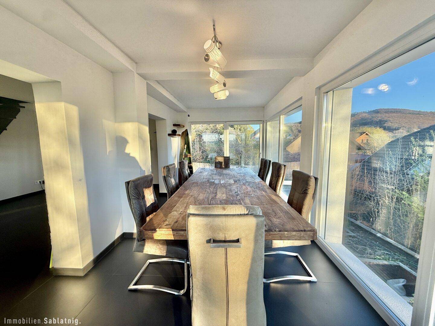 Eleganter Essbereich mit Holztisch, modernen Stühlen und hellem Ambiente.