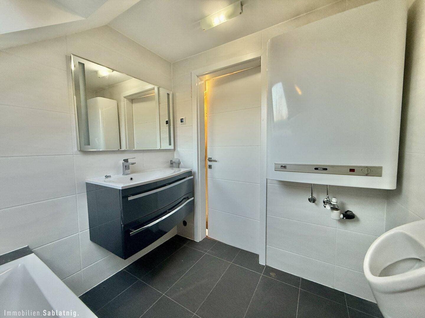 Badezimmer im Dachgeschoss mit Waschtisch, Heizung und Urinal.