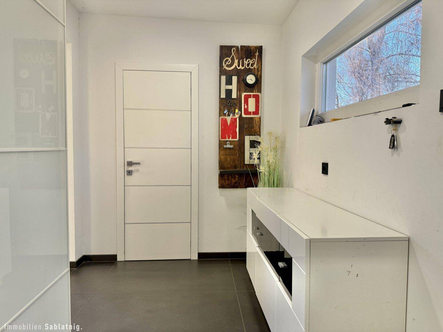 Heller Eingangsbereich mit modernem Sideboard und Fenster.