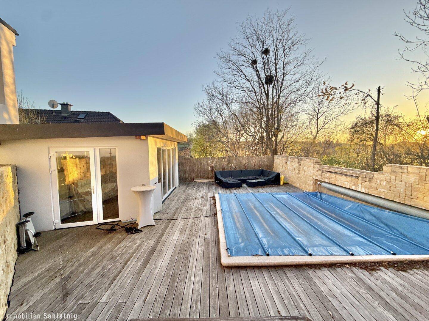 Weitläufige Holzterrasse mit Pool und Blick in die Landschaft.