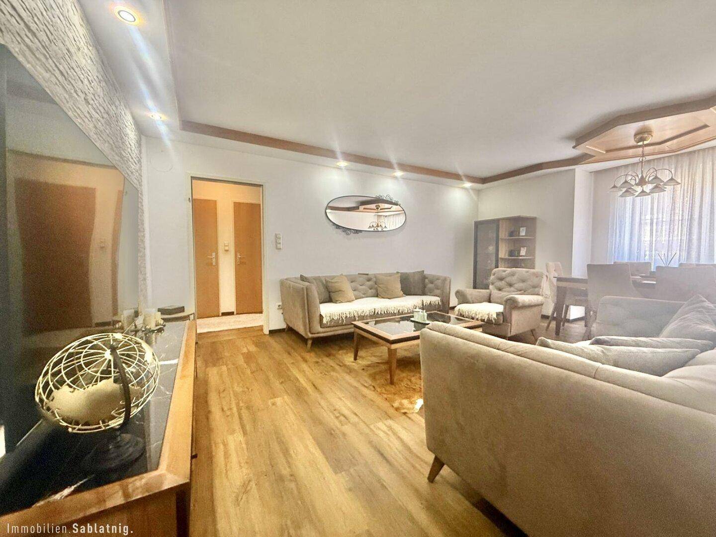 Heller Wohnbereich mit Parkettboden, gemütlichen Sofas und Blick auf den Essbereich.