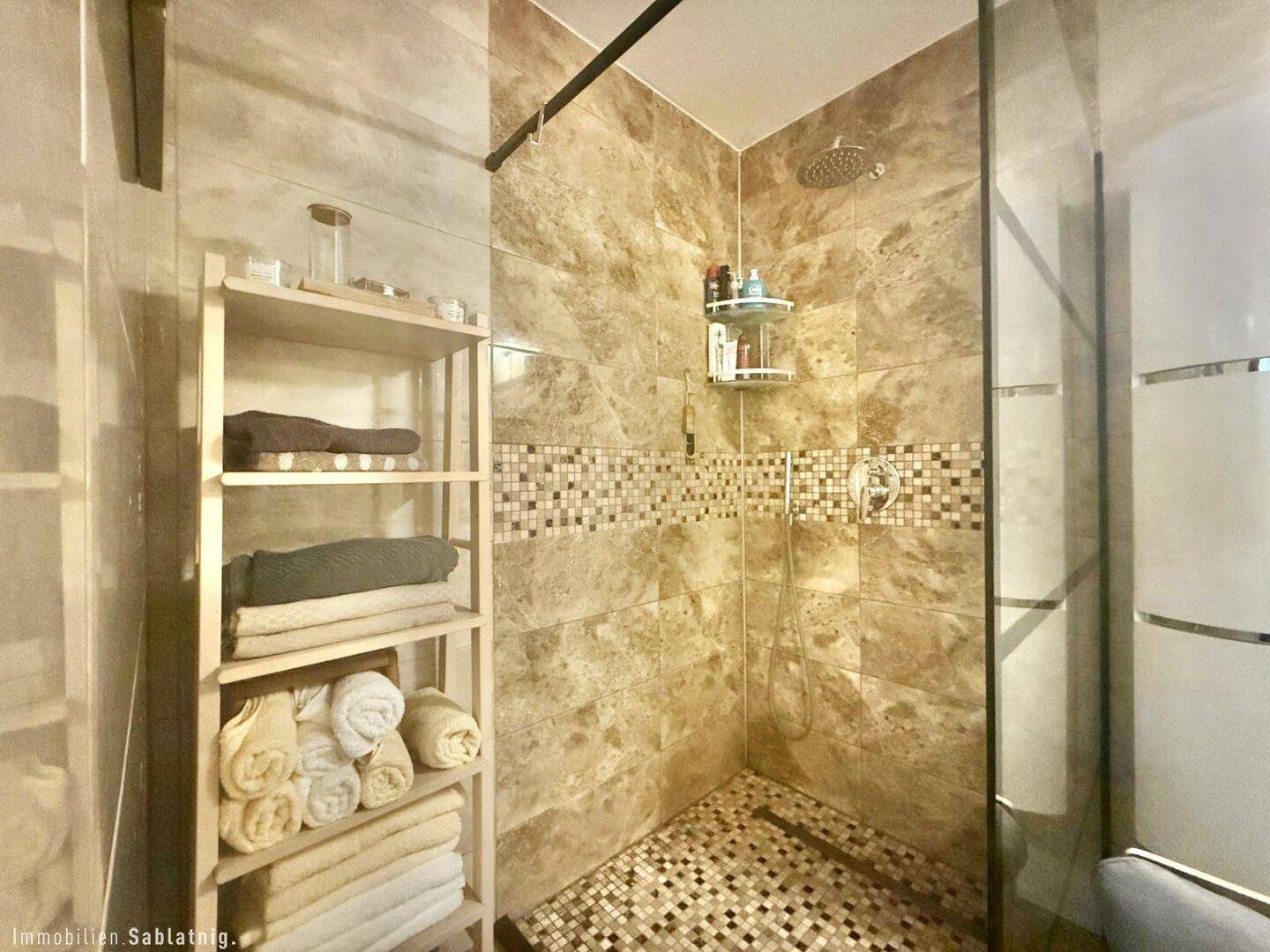 Modernes Badezimmer mit begehbarer Dusche, Fliesenboden und Wandregal.