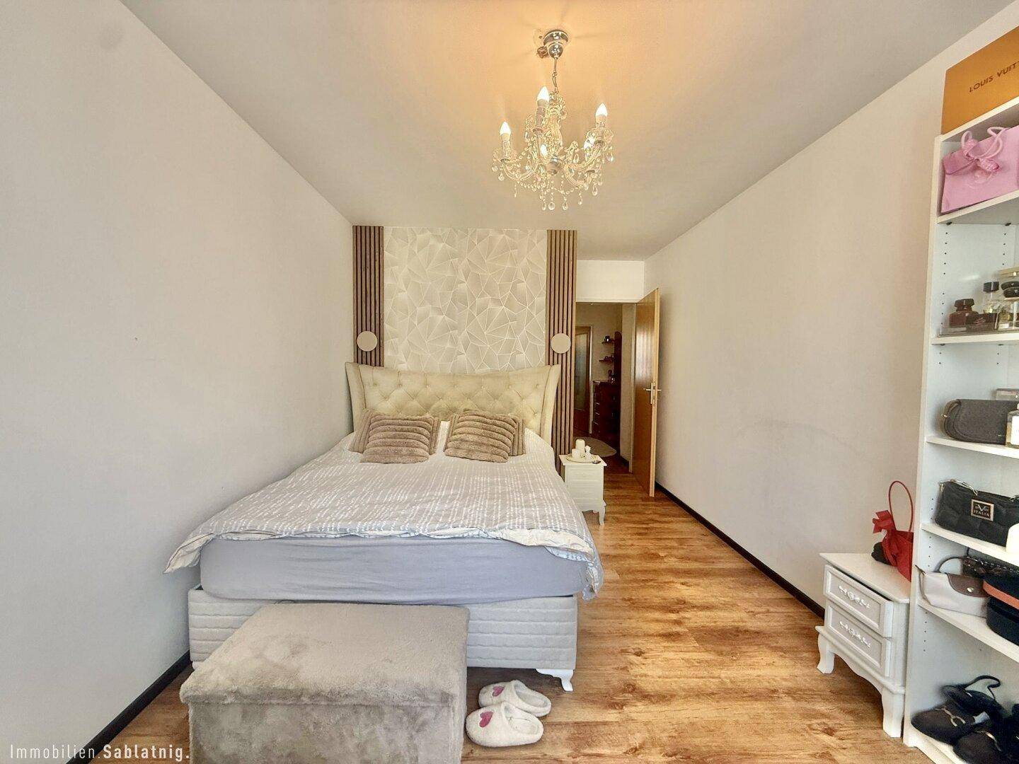 Gemütliches Schlafzimmer mit Doppelbett, dekorativer Wandgestaltung und Kronleuchter.