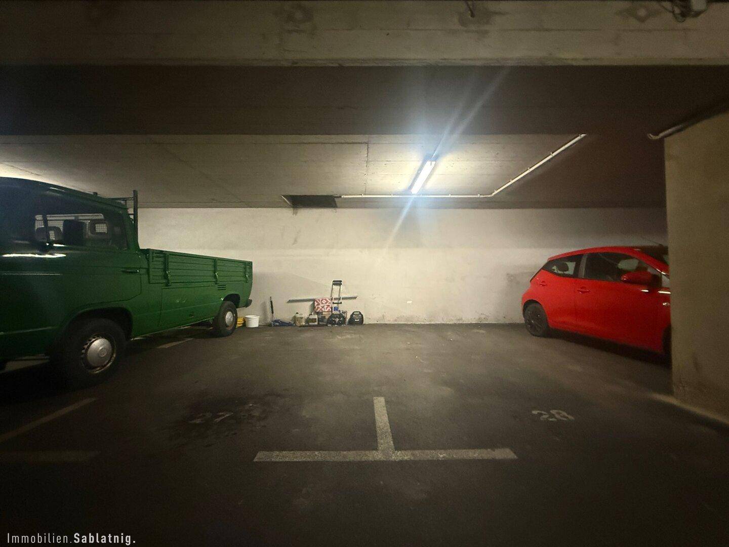 Tiefgaragenstellplatz mit ausreichend Platz für zwei Fahrzeuge und Beleuchtung.