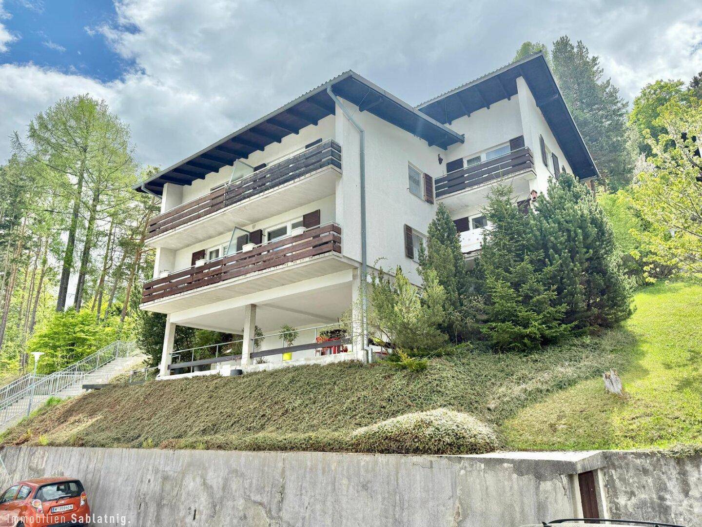Ansicht des Wohnhauses mit mehreren Etagen, Balkonen und umgebender Natur.