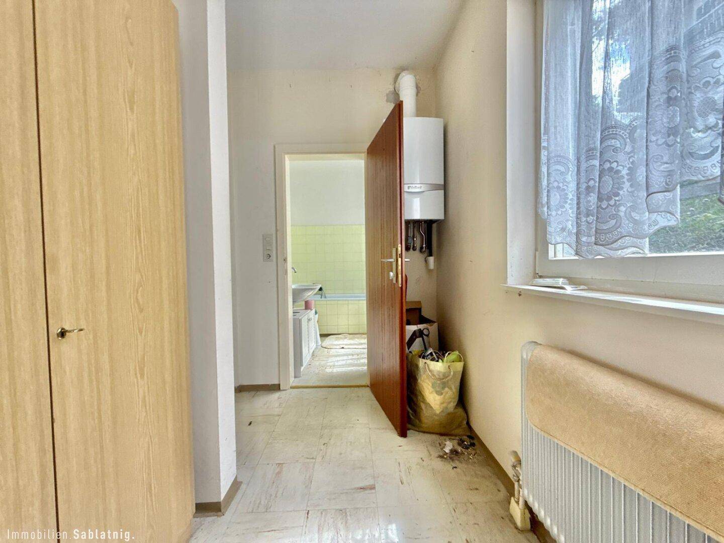 Flur mit Gastherme, Einbauschrank und Zugang zum Badezimmer.