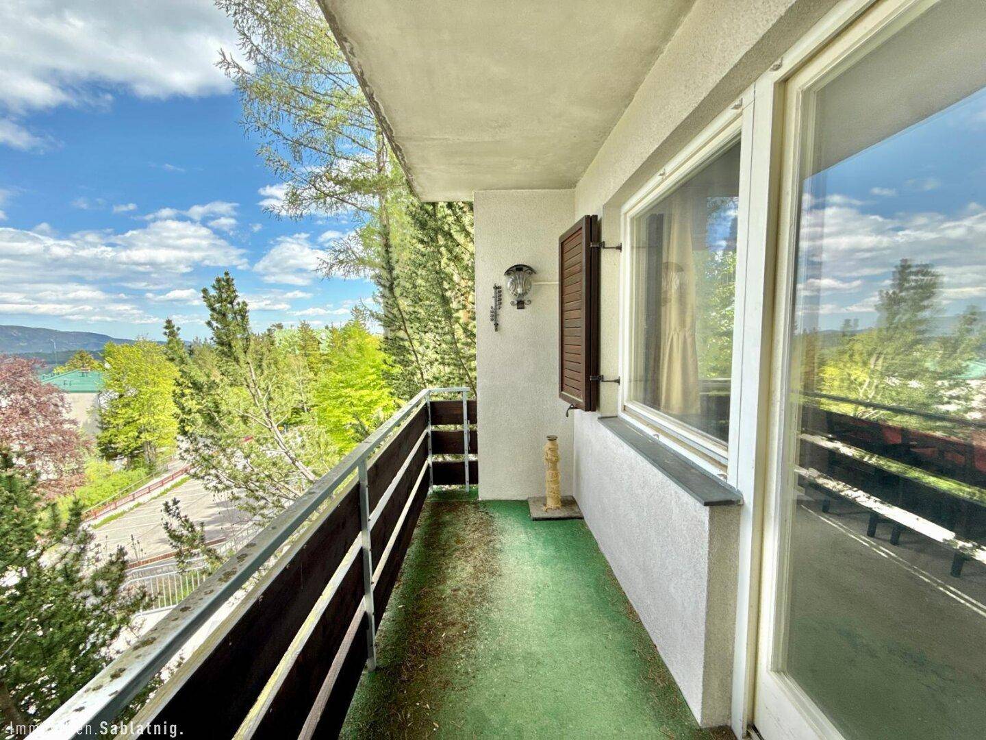 Langer Balkon mit grüner Auslegware und weitem Blick in die Natur.