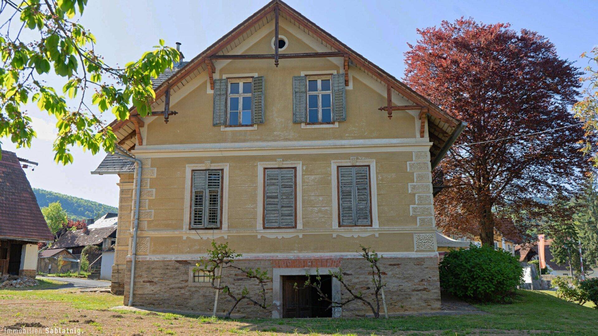 Vorderansicht des historischen Hauses mit symmetrischen Fenstern und dekorativen Elementen.
