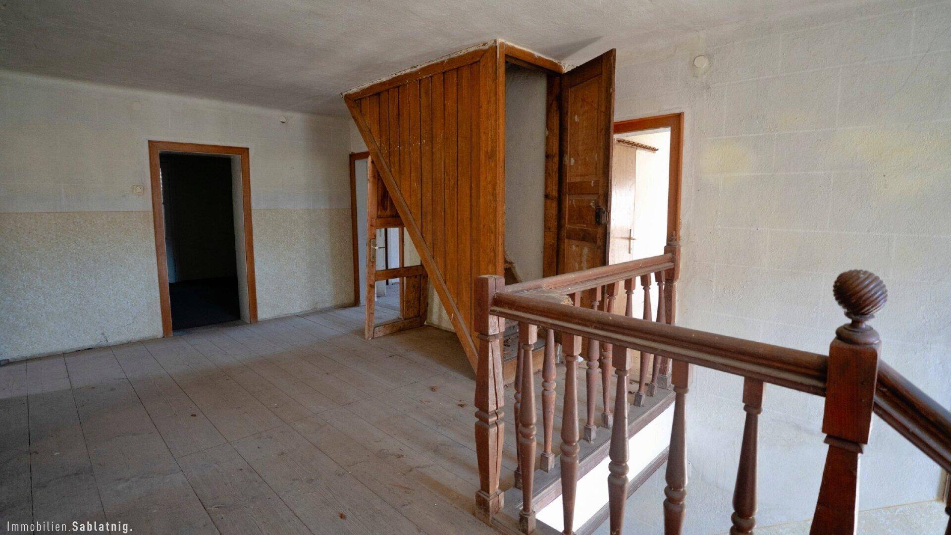 Obergeschoss-Flur mit rustikaler Holztreppe und Holzboden, der zu weiteren Räumen führt.