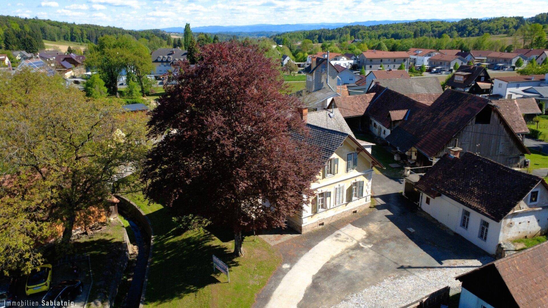 Luftaufnahme des Anwesens mit dem historischen Haus und umliegenden Gebäuden in ländlicher Umgebung.