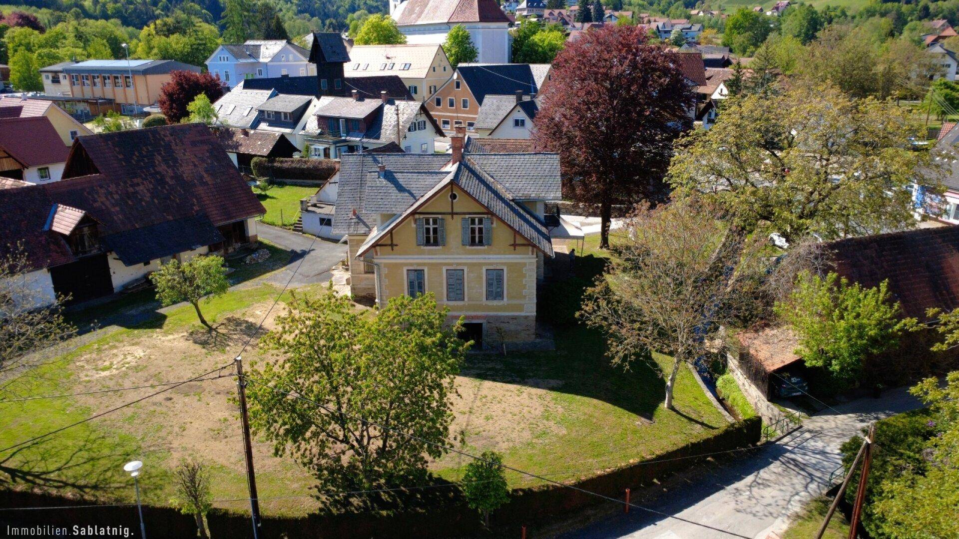Vogelperspektive auf das historische Haus und die weitläufigen Grünflächen des Anwesens.