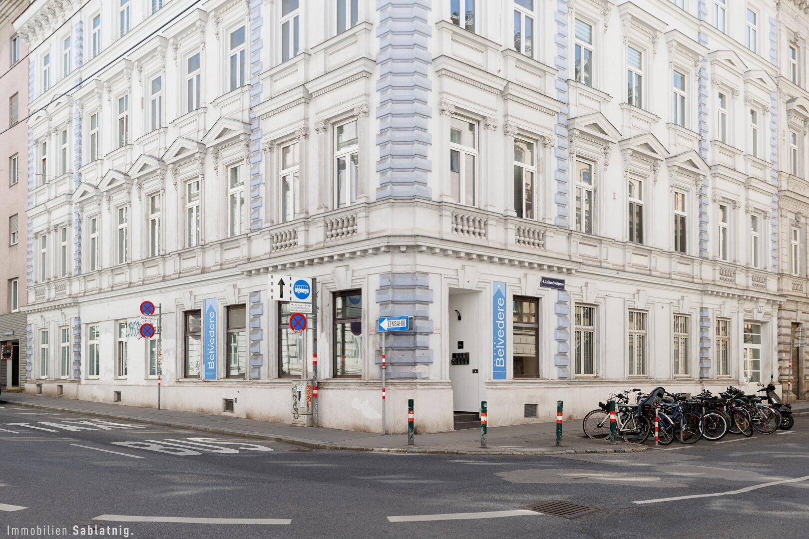 Detailansicht des Eckgebäudes mit klassischer Fassade und Beschilderung an der Straßenecke in urbaner Umgebung.