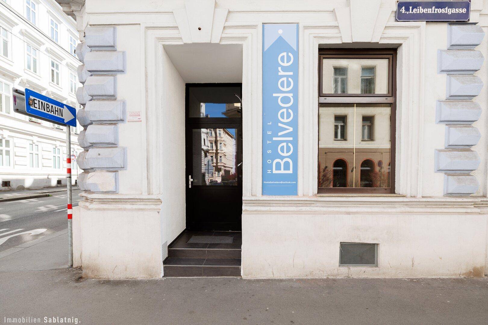 Eingangsbereich des Gebäudes mit einer schwarzen Tür und einem Fenster, umgeben von klassischer Architektur.