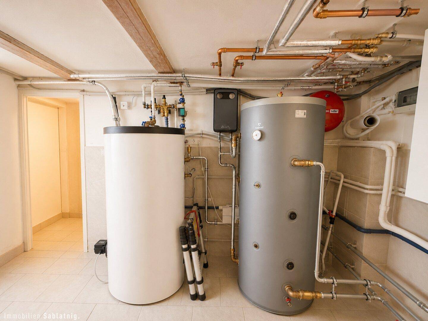 Heizungsraum mit zwei großen Warmwasserspeichern und sichtbaren Rohrleitungen.