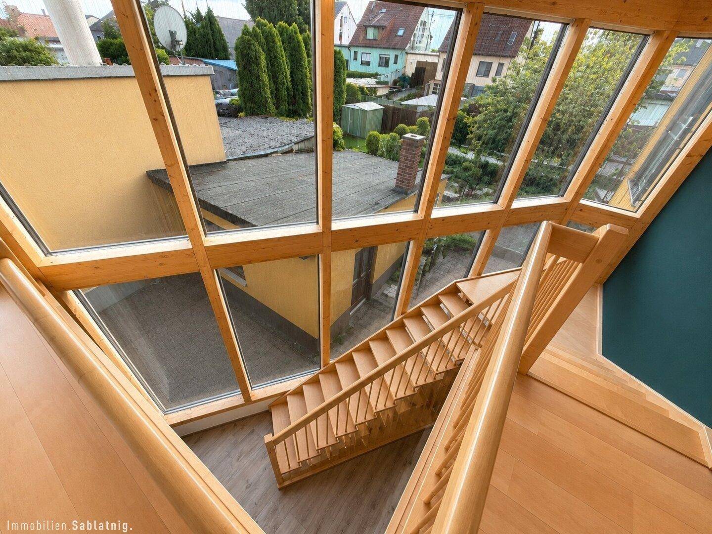 Offenes Treppenhaus mit großen Glasflächen und Blick auf die Umgebung.