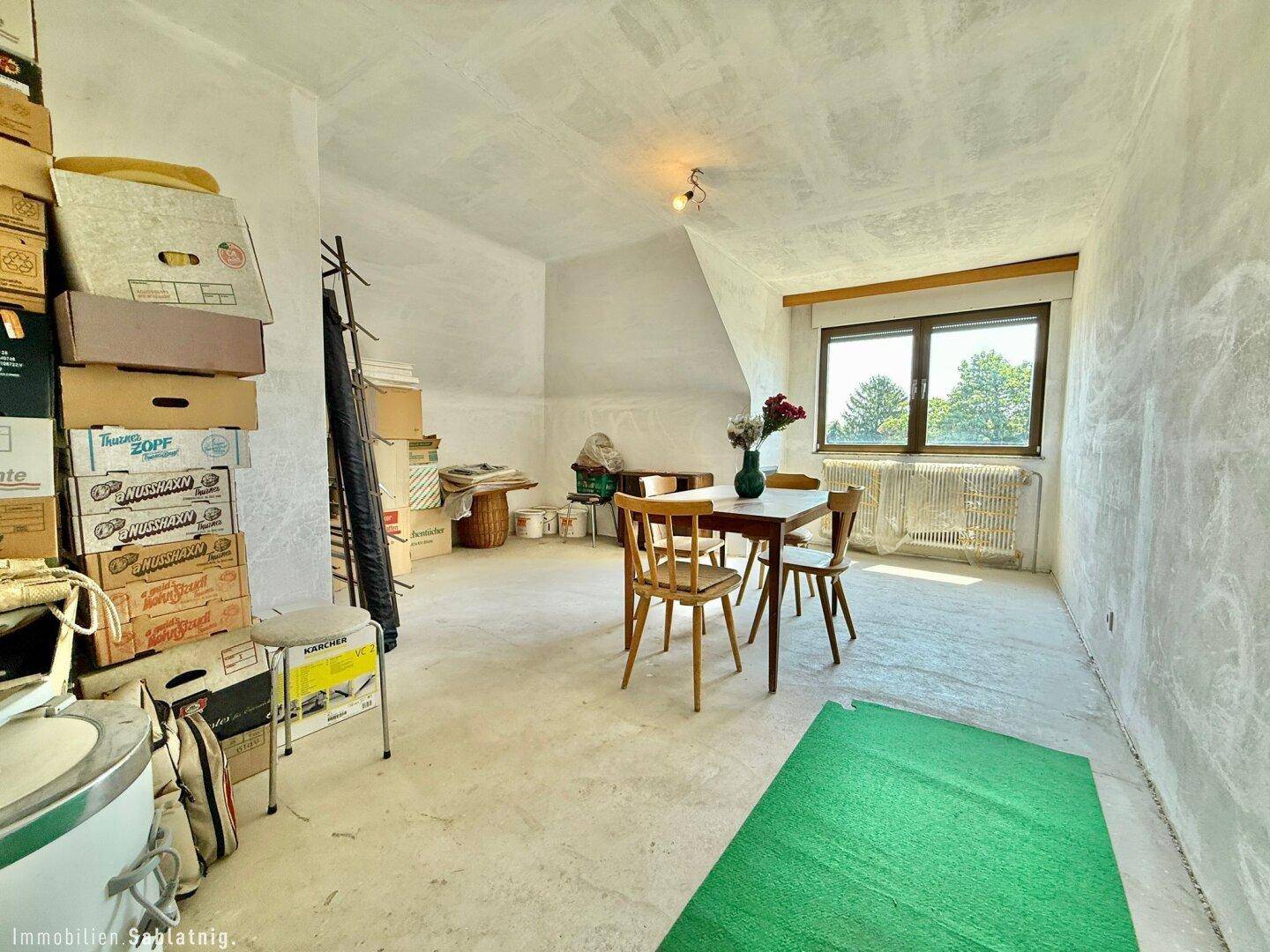 Essbereich im Dachgeschoss mit Tisch, Stühlen und Blick ins Grüne.