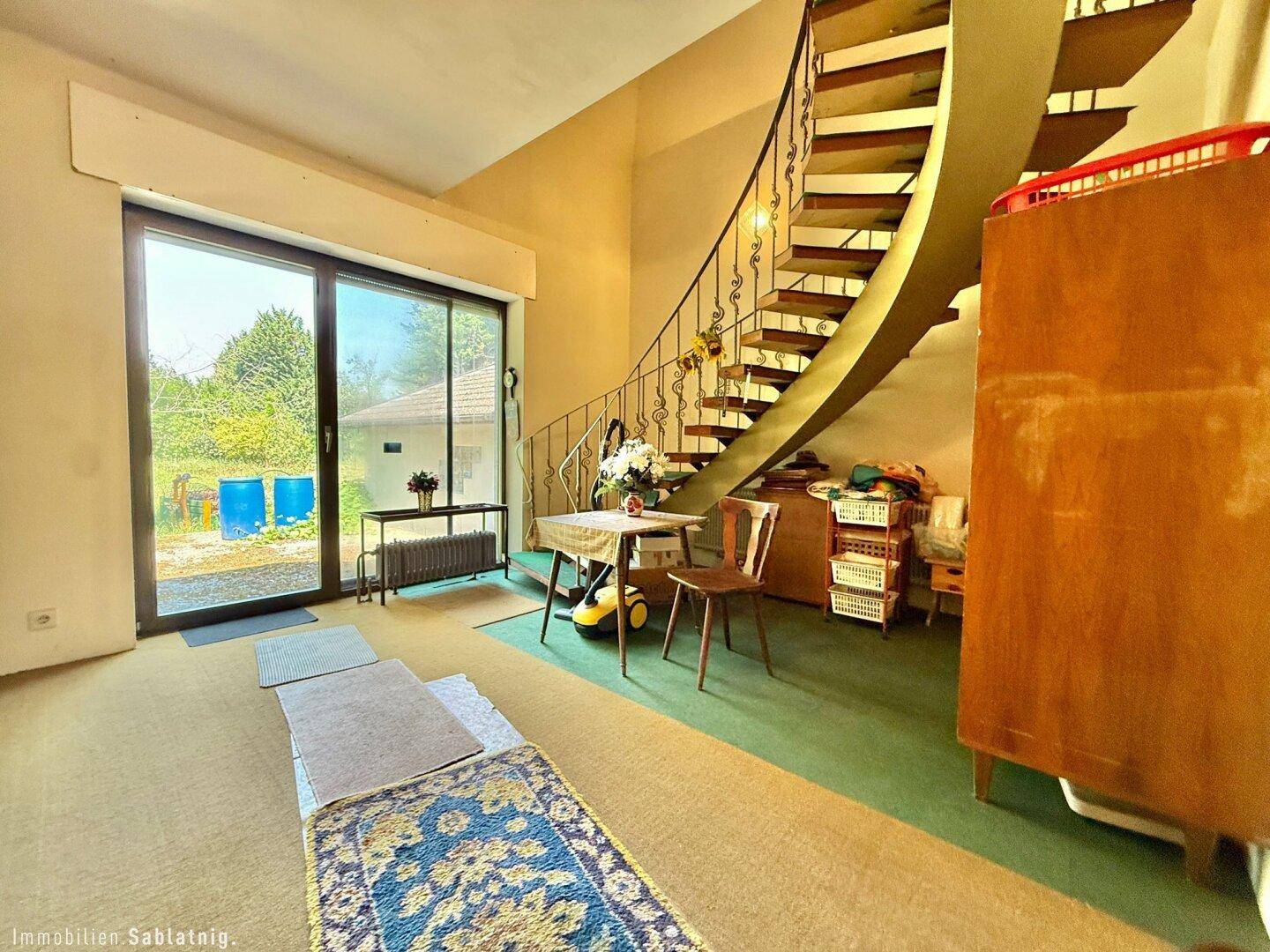 Wohnbereich mit Wendeltreppe, Teppichboden und Zugang zum Garten.
