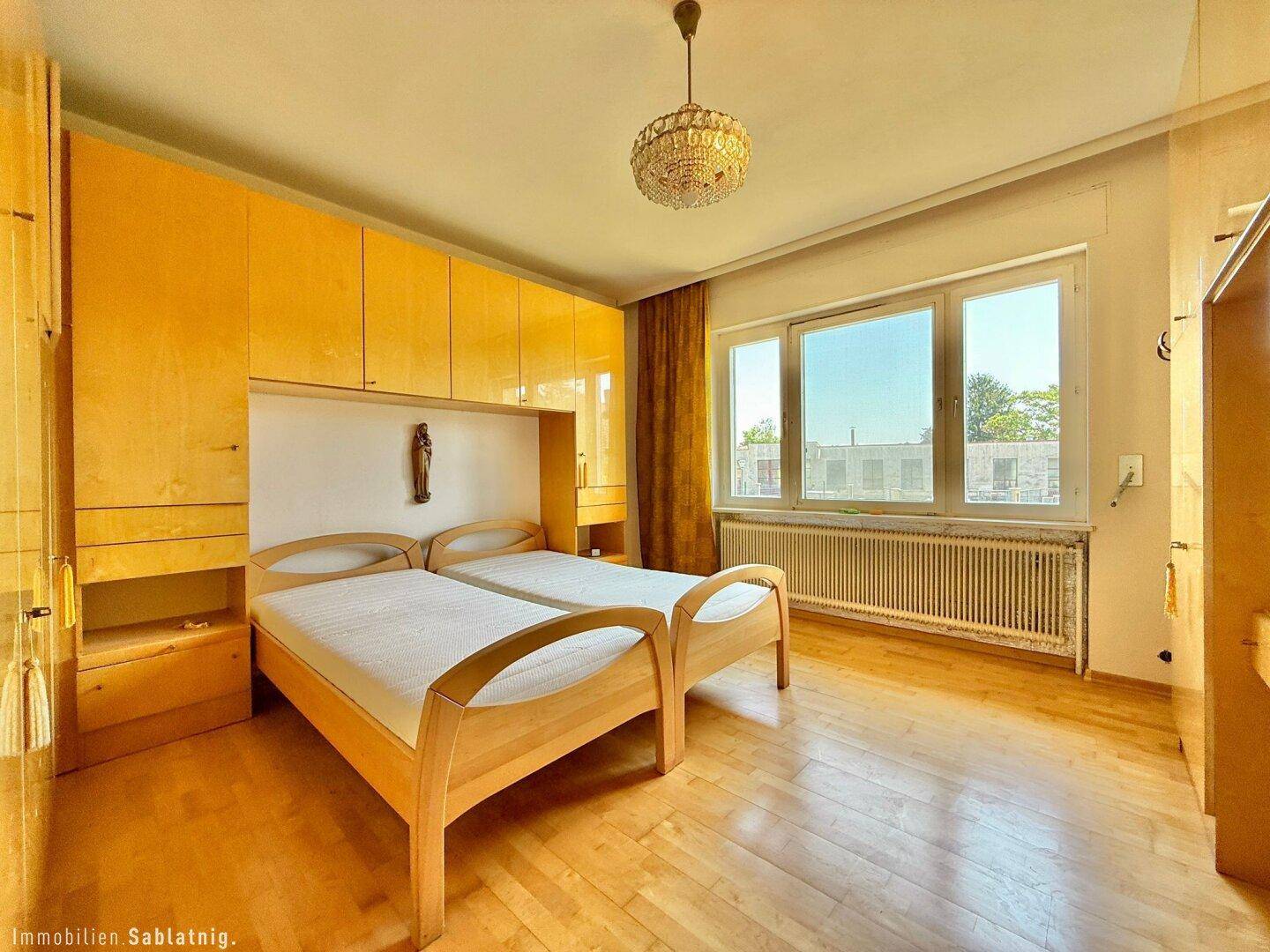 Helles Schlafzimmer mit zwei Einzelbetten, Einbauschränken und Parkettboden.