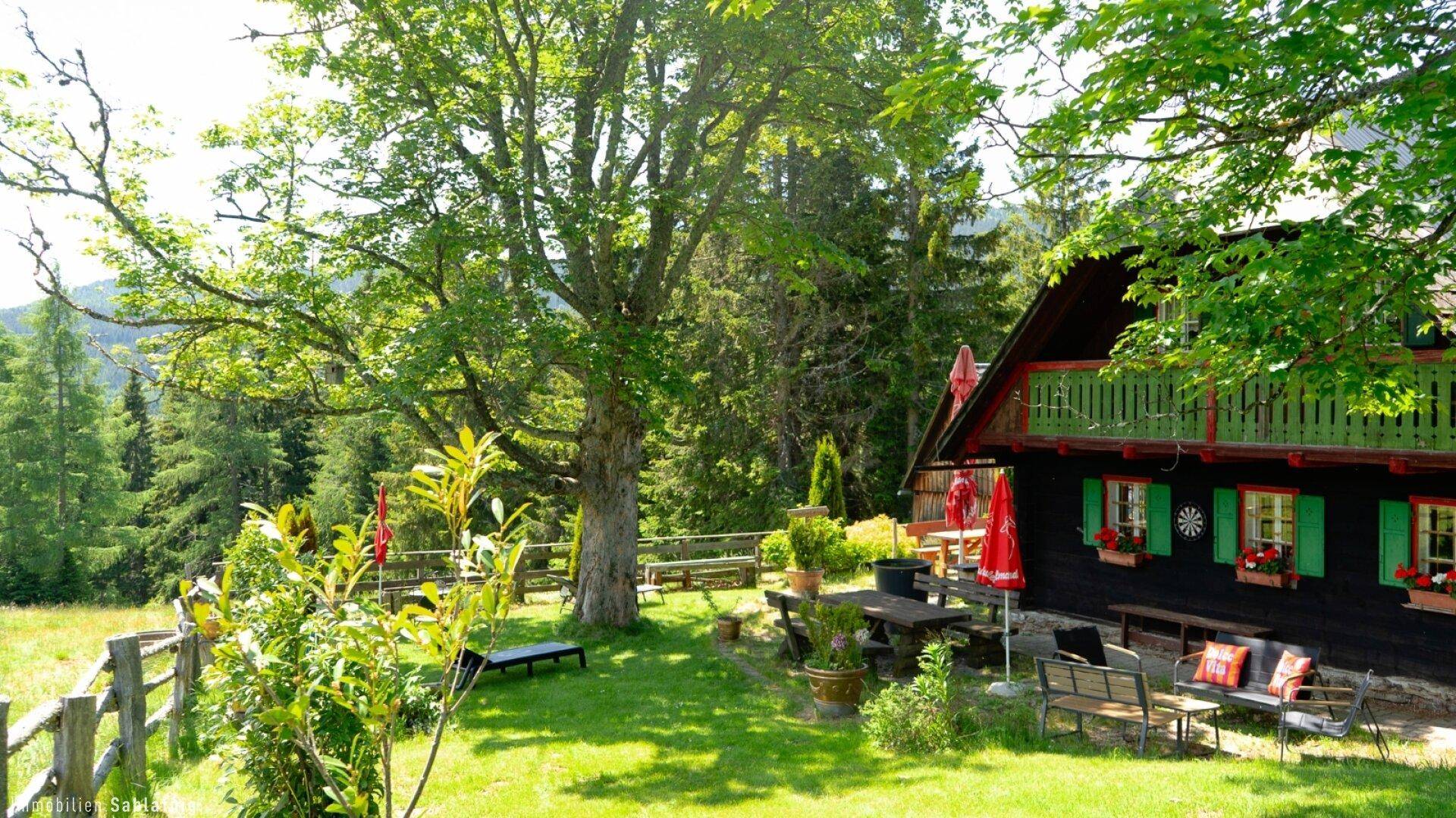 Charmantes Holzhaus mit Balkon und großzügigem Gartenbereich, umgeben von üppiger Natur.