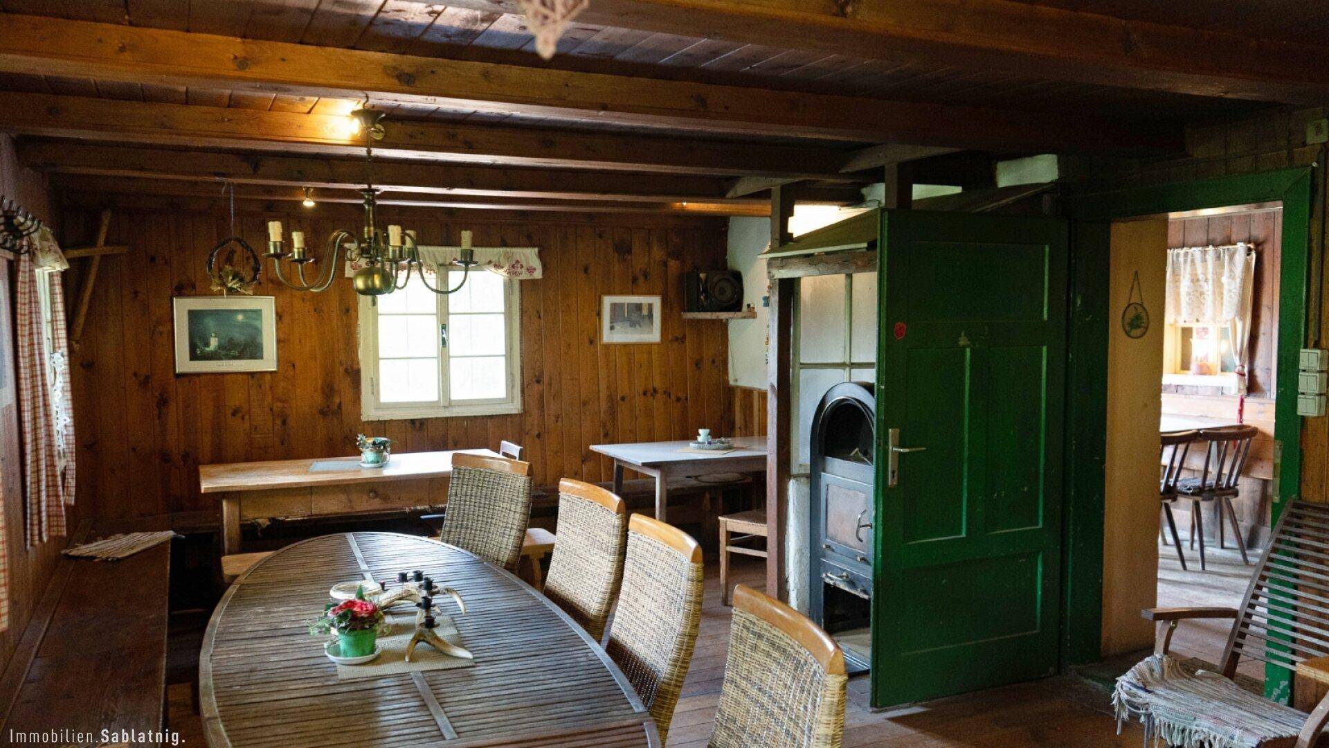 Geräumiger Wohn- und Essbereich mit Holztäfelung, Kaminofen und rustikalem Charme.