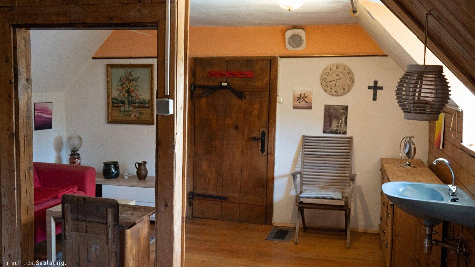 Rustikaler Eingangsbereich mit Holztür, Holzboden und einem kleinen Waschbecken.