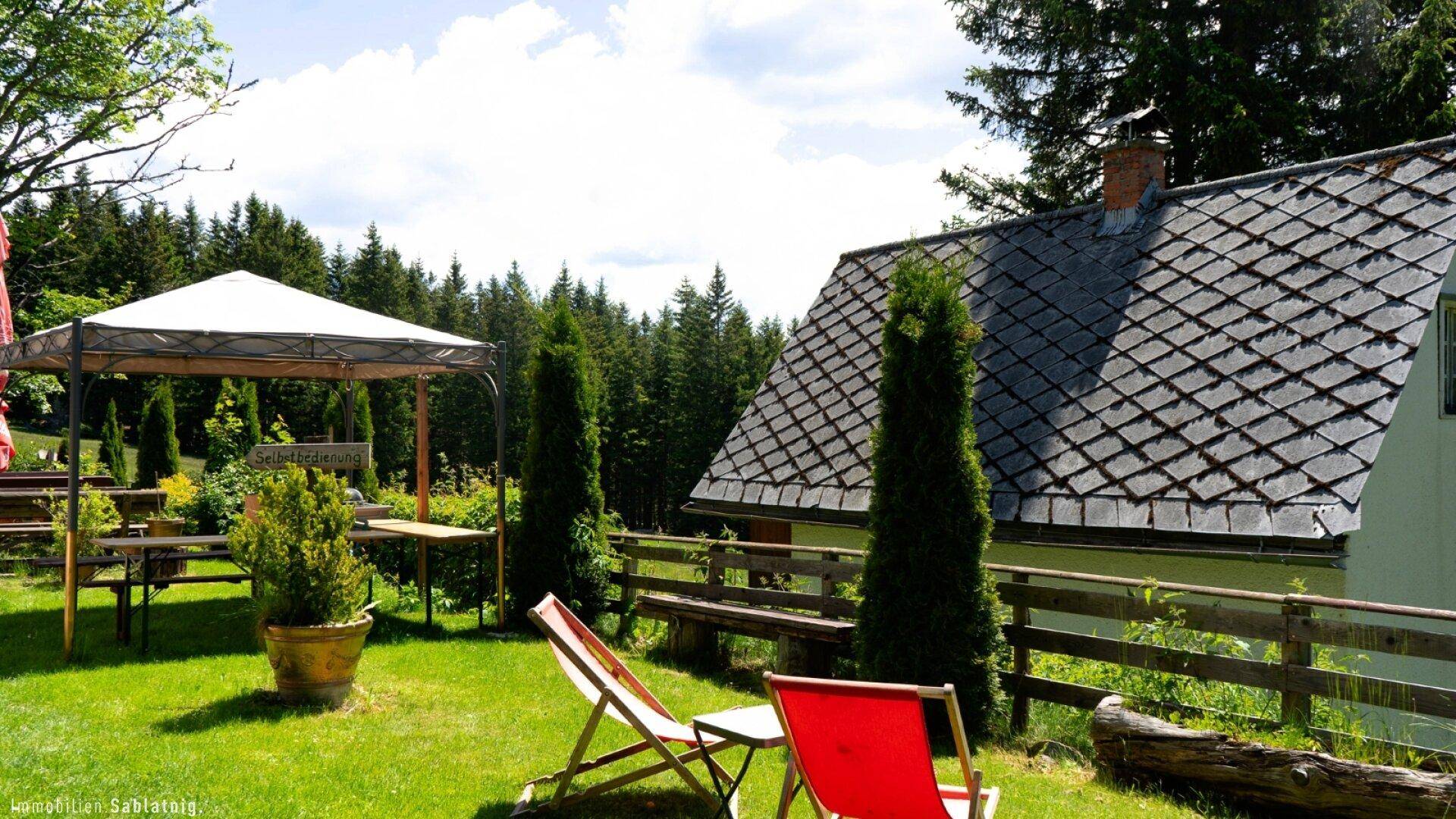 Gemütlicher Gartenbereich mit Pavillon, Sonnenliegen und Blick auf das traditionelle Hausdach.