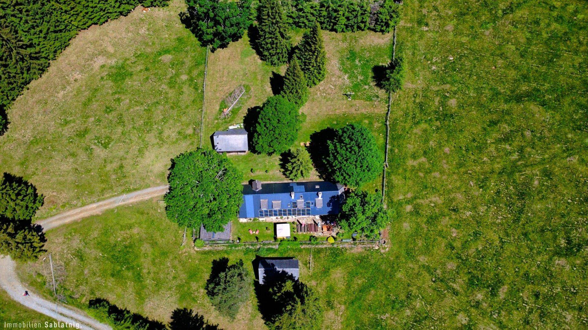 Weitläufige Luftaufnahme des Anwesens mit dem Haupthaus, Nebengebäuden und weitläufigen Grünflächen.