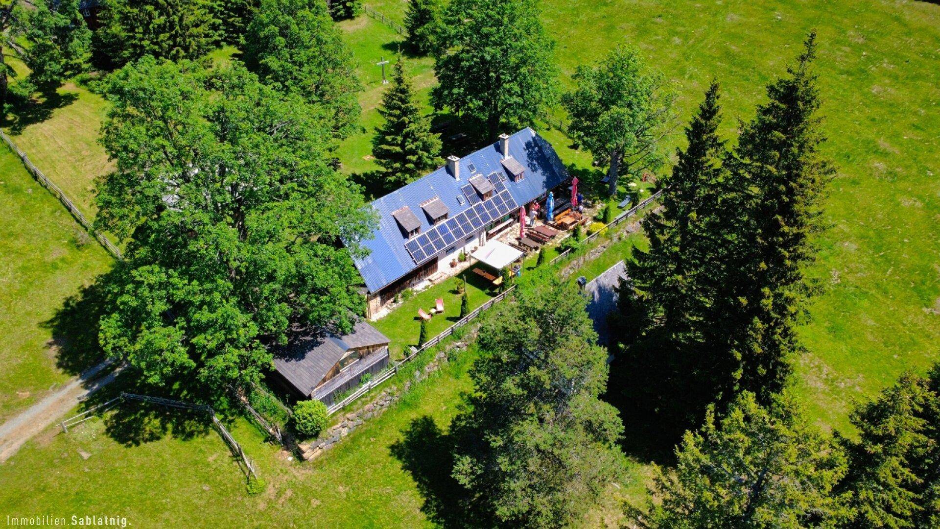 Nahaufnahme aus der Luft des Hauses mit Solaranlage, Außenbereich und der umliegenden Natur.