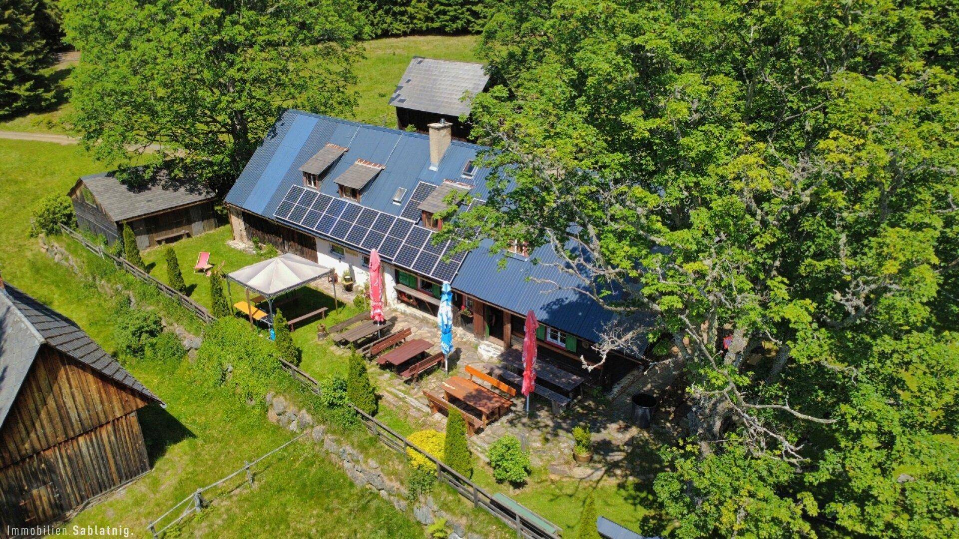 Detaillierte Luftaufnahme des Hauses mit Solarpaneelen und den vielfältigen Außenbereichen für Entspannung.