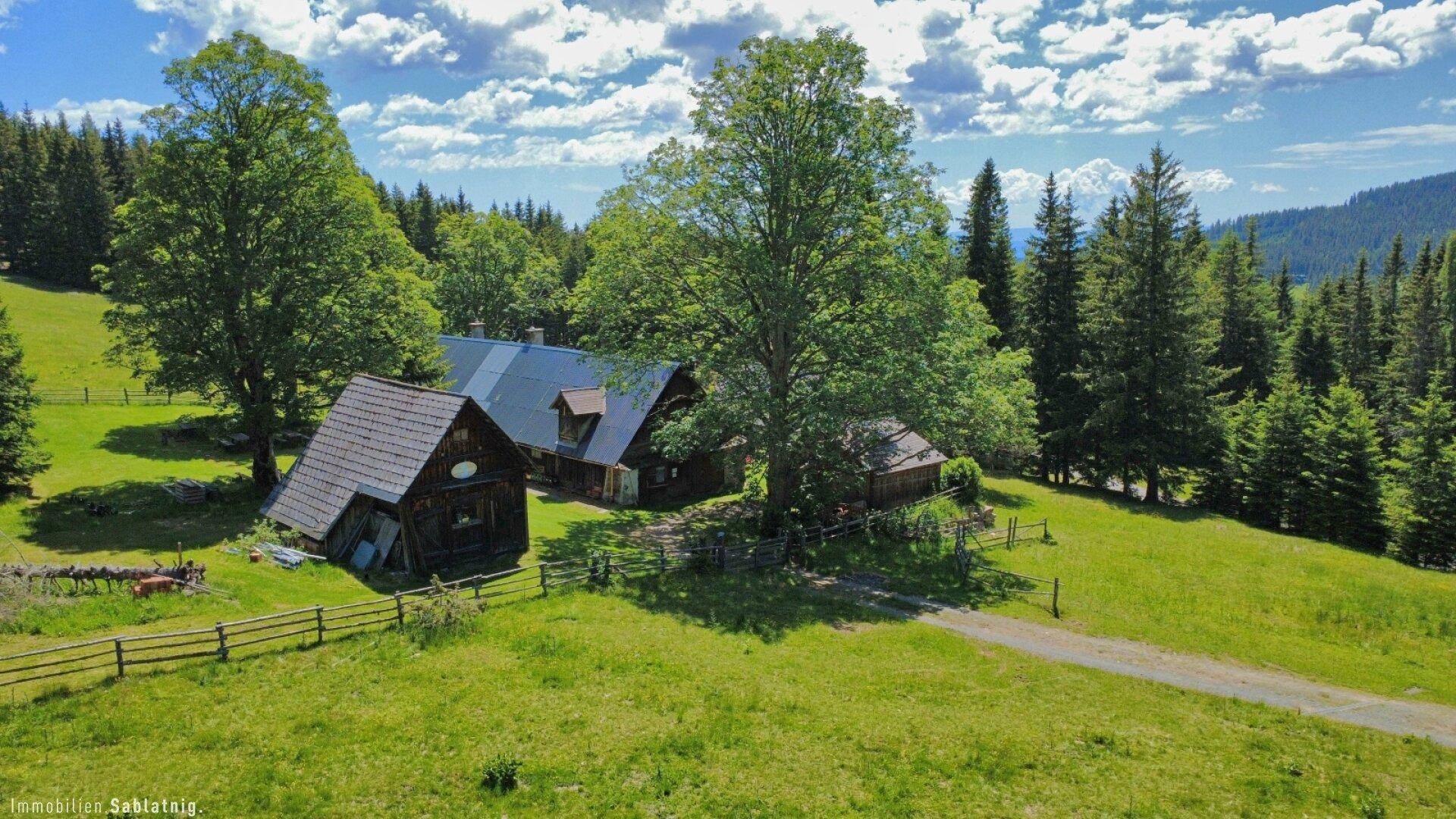 Großzügige Luftaufnahme des Anwesens, eingebettet in eine weite Naturlandschaft mit Wäldern und Bergen.