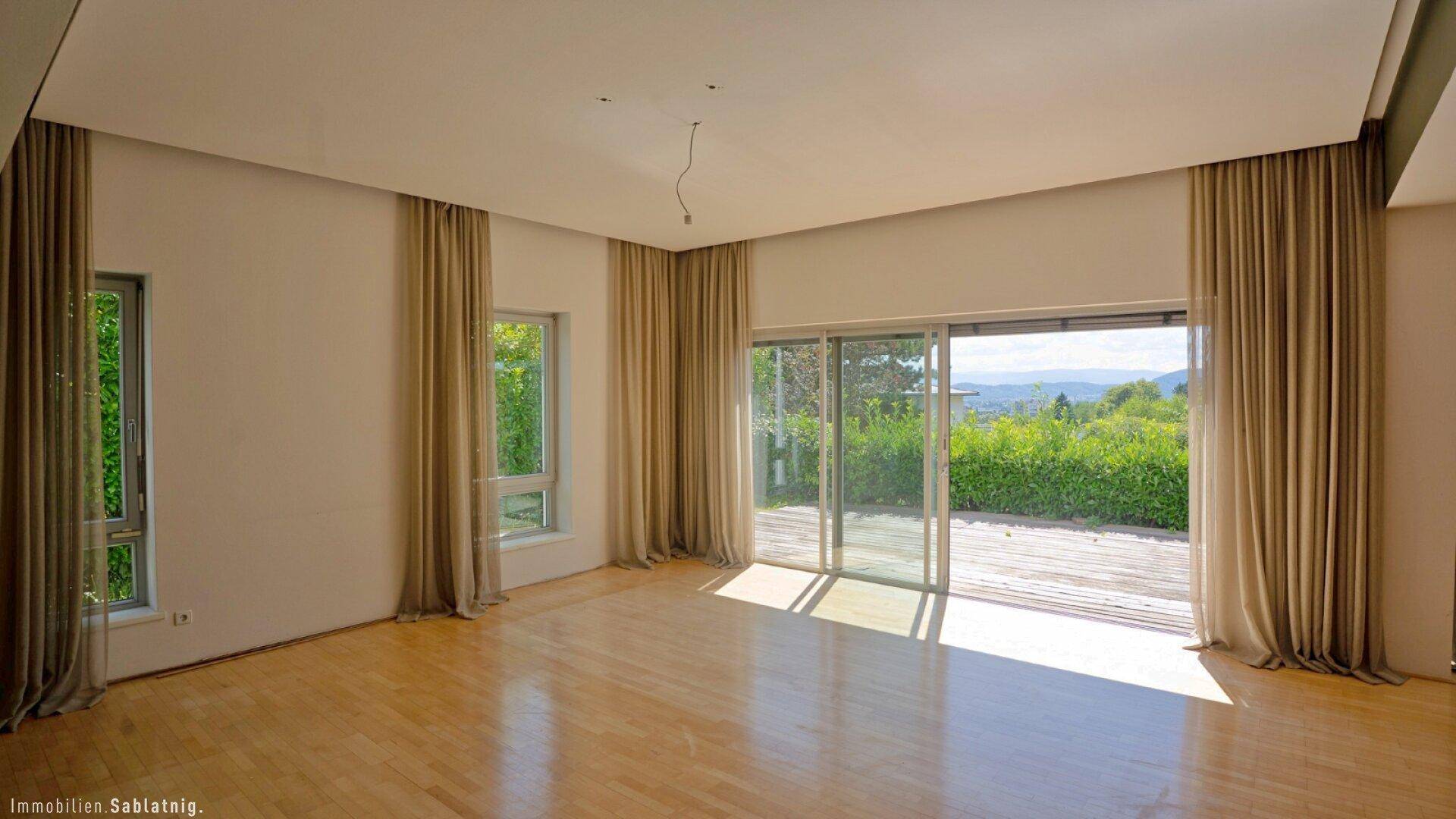 Lichtdurchflutetes Wohnzimmer mit Zugang zur Terrasse und weitem Blick über die Landschaft.
